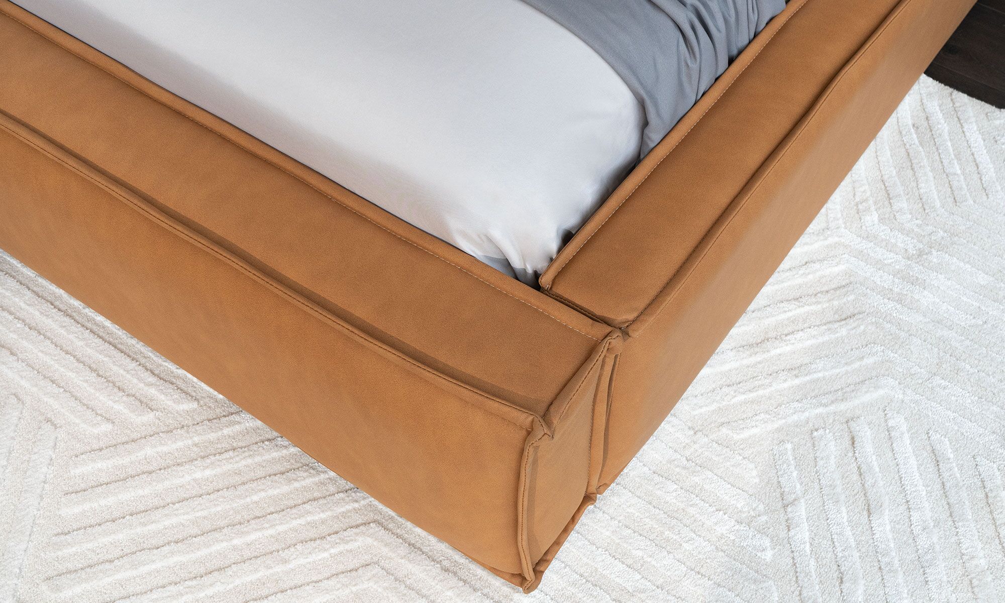 CAMA-PALERMO-1-Ambiente Cama Palermo de la marca Aristas vista en detalle. Presenta una estructura robusta y elegante, con un cabecero acolchado y líneas rectas en el color de tela Nobuck Bronce.