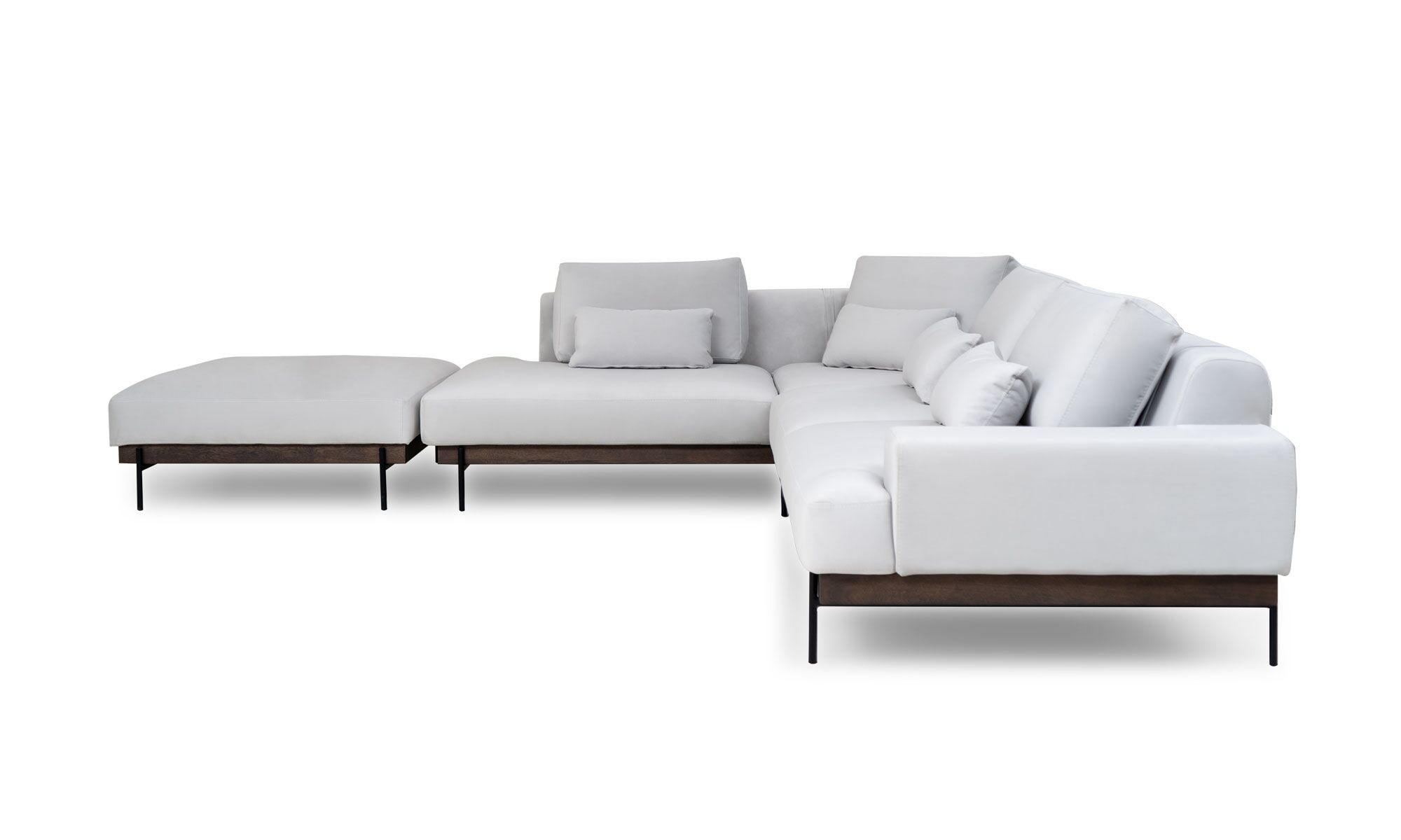 frente ( L MAIA + PUFF Vista lateral de la Sala En L Modular Maia con puff, de la marca Aristas. Un diseño contemporáneo, tapizado en tela suave de color neutro, base en madera y patas metálicas. El puff, con el mismo estilo y material, complementa el conjunto.