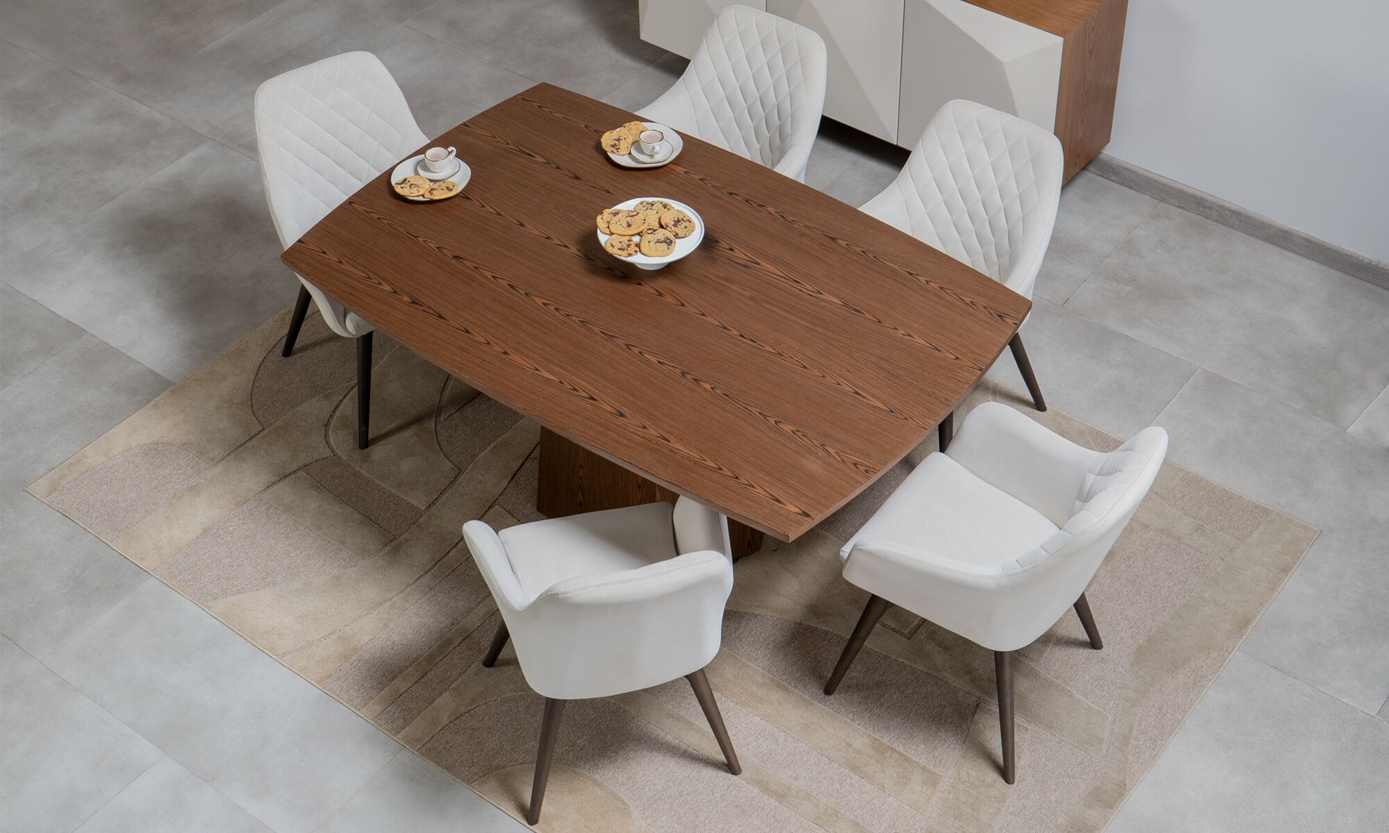 Mesa comedor Milano + 6 sillas Odense Mesa Comedor Milano + 6 Sillas Odense de Aristas vista desde arriba. La mesa cuenta con una superficie rectangular curva, de líneas limpias y acabados pulidos, y, las sillas Odense tienen un respaldo acolchado y tapizado elegante que complementa el conjunto.