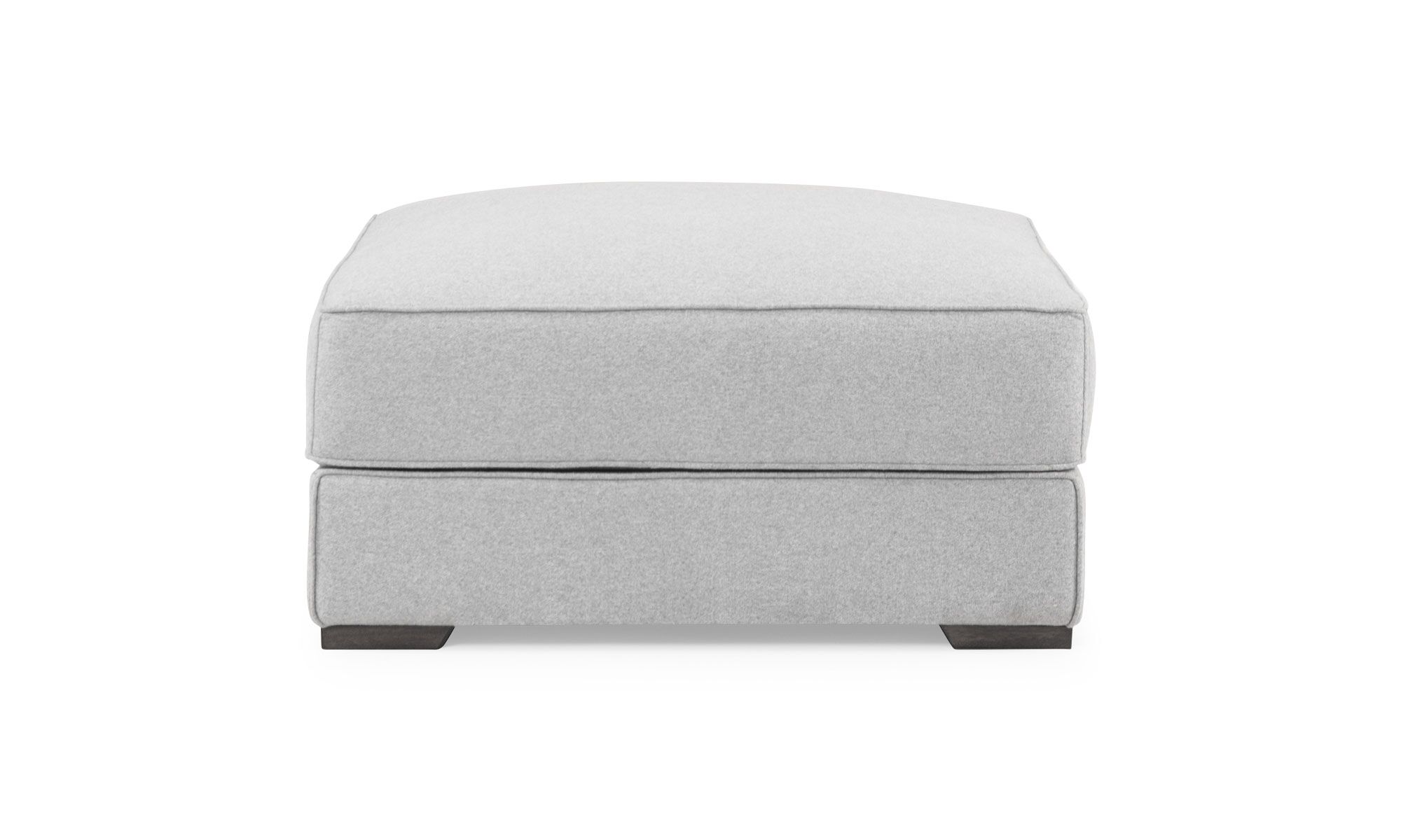 1-Puff-Roma Vista frontal del Puff Roma de la marca Aristas. Este puff compacto tiene un diseño cuadrado y elegante, con un tapizado uniforme en tono neutro y patas discretas en madera.