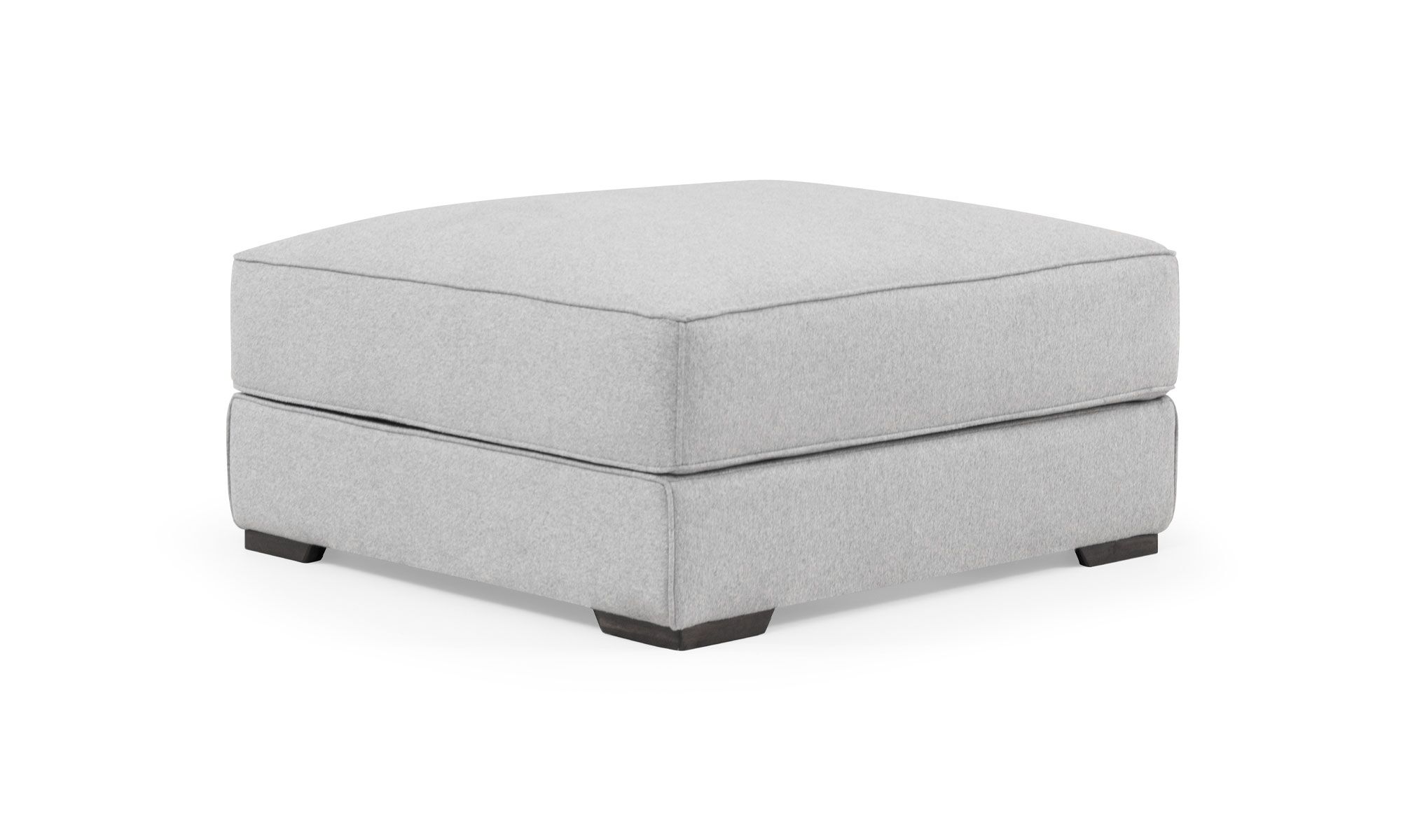 2-Puff-Roma Vista diagonal del Puff Roma de la marca Aristas. Este puff compacto tiene un diseño cuadrado y elegante, con un tapizado uniforme en tono neutro y costuras discretas en sus bordes. Su estructura simple y acolchada ofrece comodidad y versatilidad.