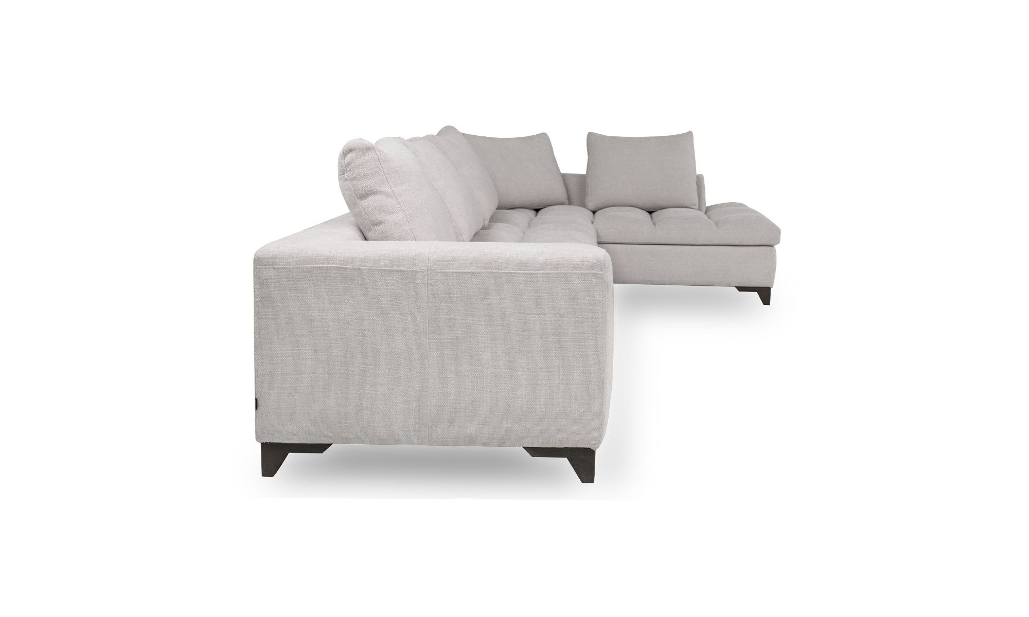 Modular Con Poltrona Y Puff Vitaro Plus Plumas lado Vista lateral del Modular con Poltrona y Puff Vitaro Plus Plumas de Aristas. Este conjunto modular se compone de un sofá espacioso con una poltrona y un puff adicionales. Tienen un tapizado en tela suave, con un asiento acolchado y cojines en el respaldo. La poltrona y el puff mantienen el mismo estilo, complementando el conjunto.