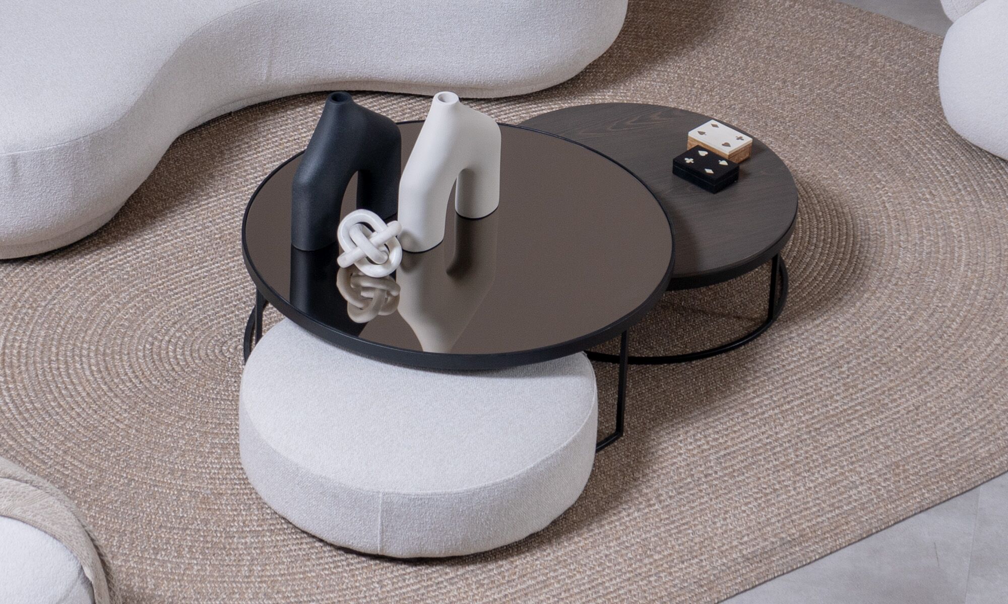 Puff Luna Juego de Mesa Centro Luna Mad 90 y Puff Luna 70 de la marca Aristas vistas en perspectiva diagonal. El conjunto presenta un diseño moderno y elegante. La mesa tiene una estructura robusta y minimalista en madera color Ceniza, mientras que el puff complementa el conjunto con una estética igualmente sencilla y armónica.