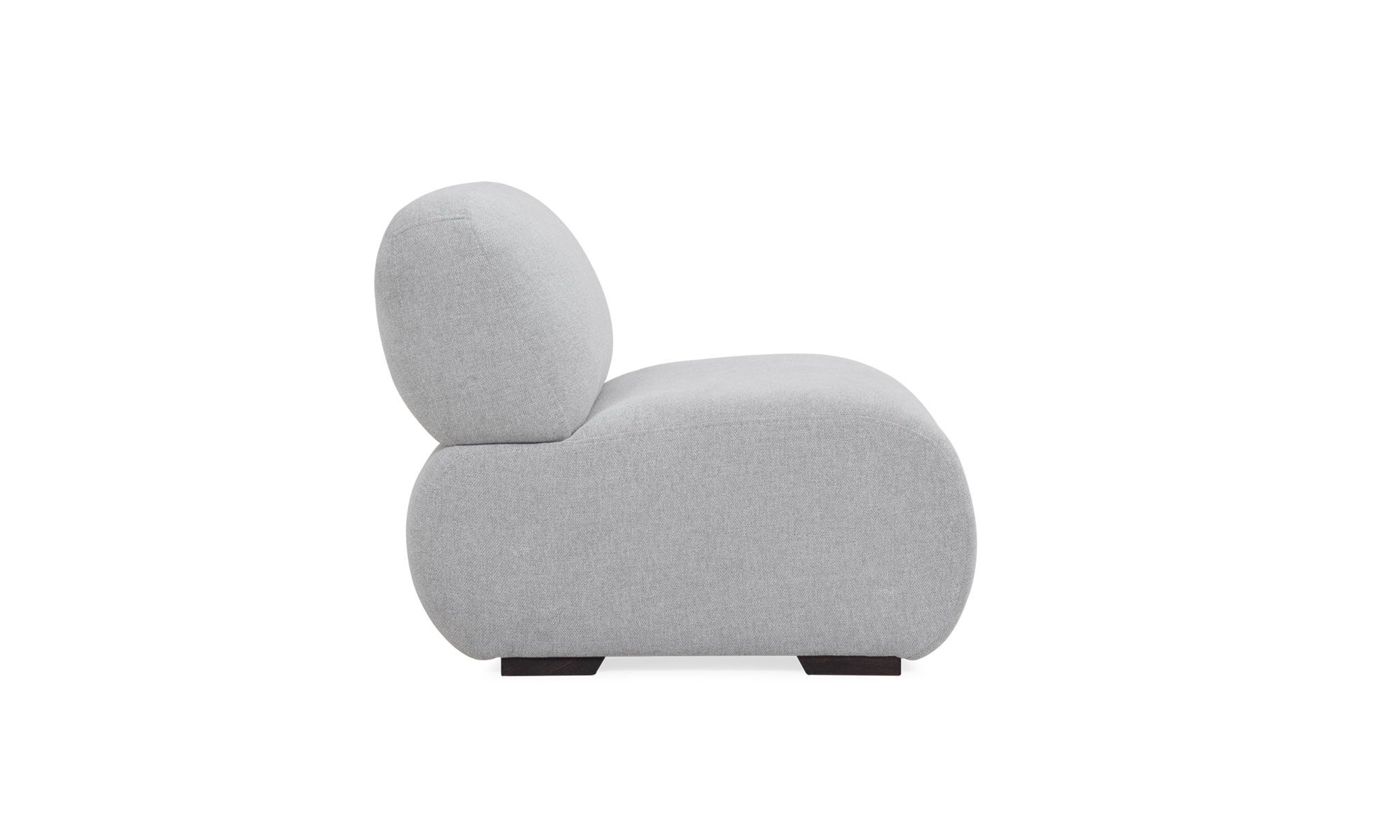 3.POLTRONA-EMMA Poltrona Emma de la marca Aristas, vista en perspectiva lateral. Destaca por su diseño sofisticado de líneas curvas, con un respaldo y asiento acolchados. Su estructura es robusta y está tapizada en tela suave.