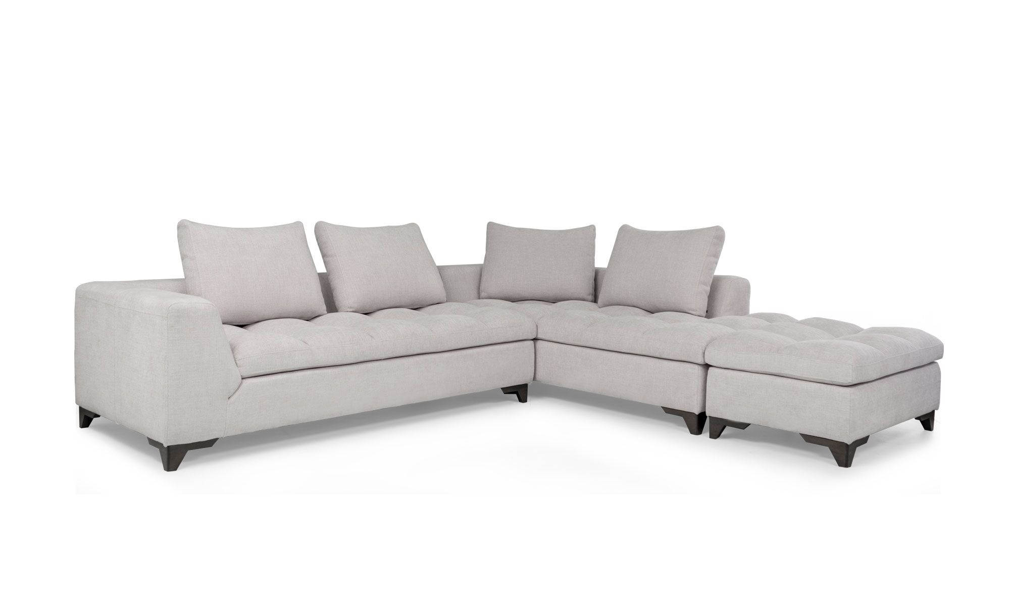 Modular Con Puff Vitaro 3,4 Vista diagonal del Modular con Puff Vitaro Plus Plumas de Aristas. Un diseño moderno con un tapizado suave y elegante, su asiento es acolchado y sus patas discretas en madera color Ceniza. El puff tiene el mismo estilo del sofá y complementa el conjunto.
