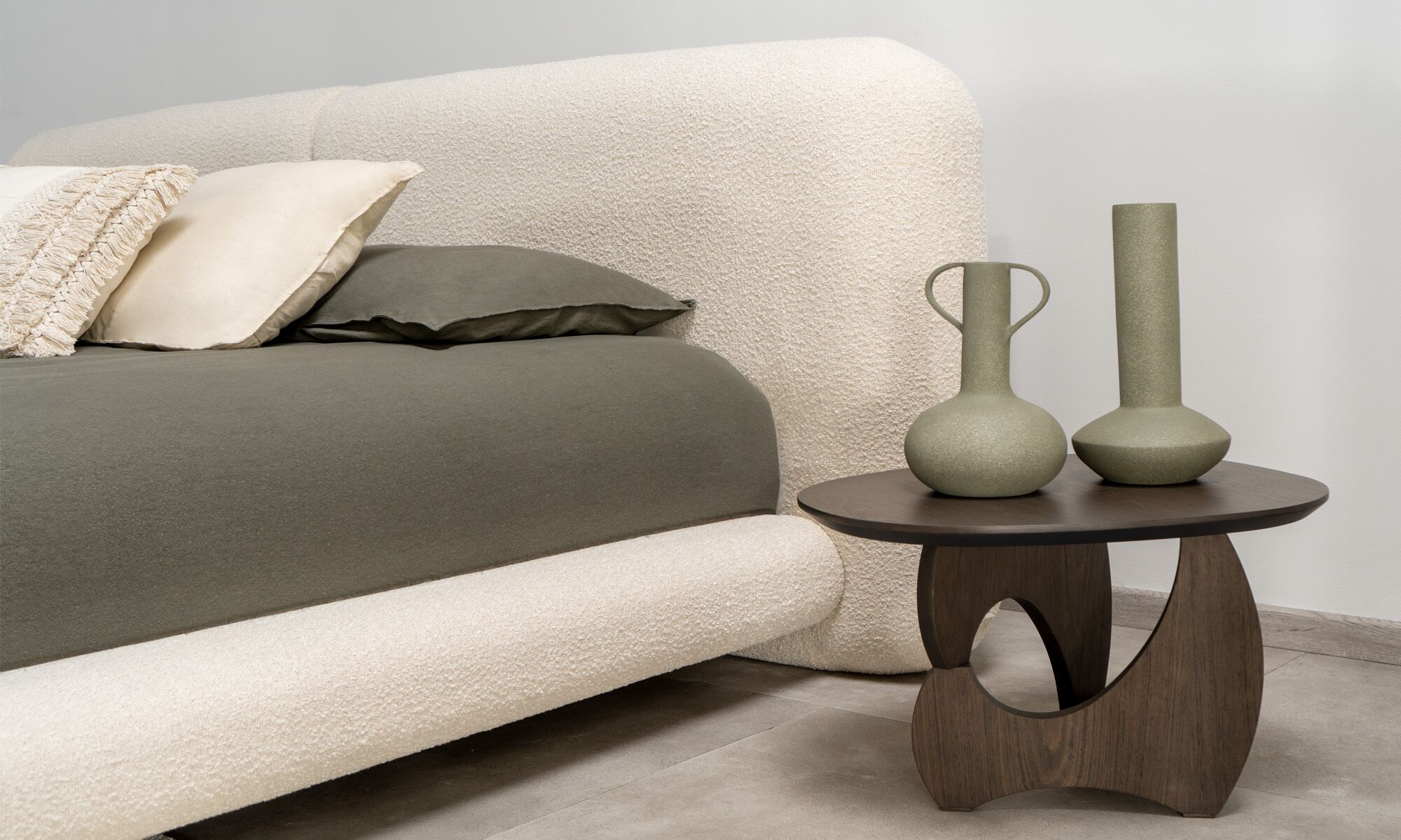 Cama milan-1 Vista en detalle de la Cama Milán de la marca Aristas. Un diseño elegante y minimalista que destaca por su cabecera acolchada de líneas curvas y tapizado suave.